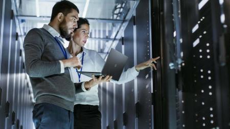 Man and woman scientist discussing in front of a supercomputer